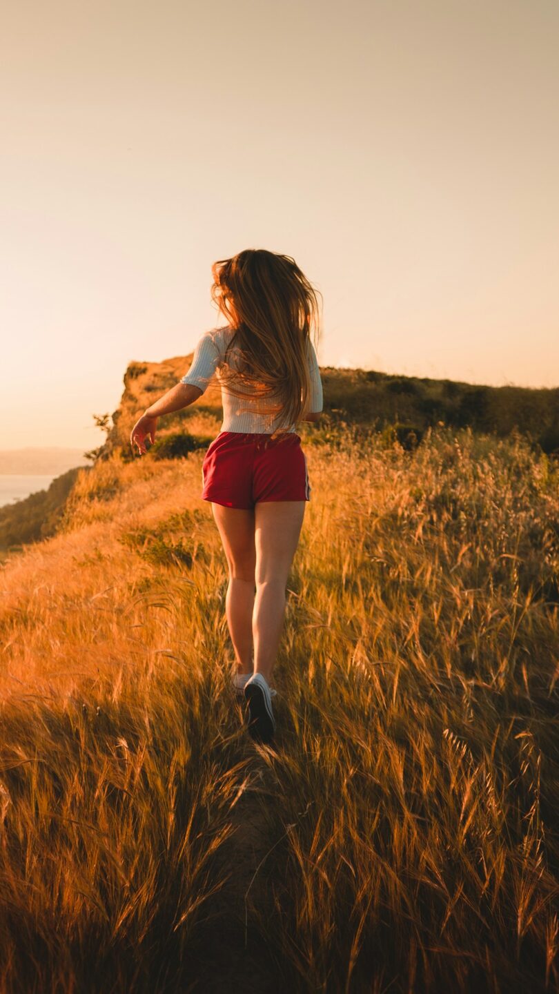 Runner climbing a golden hillside trail at sunset