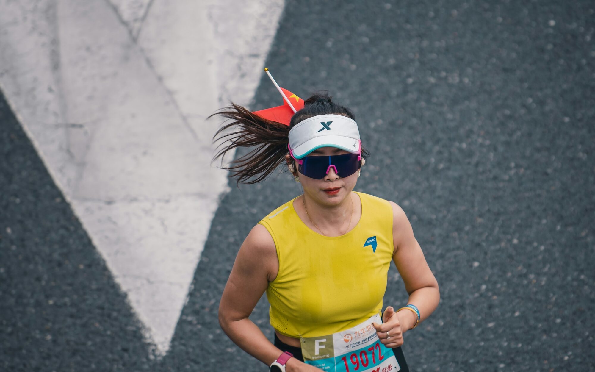Runner in a yellow singlet striding over a road arrow on race day